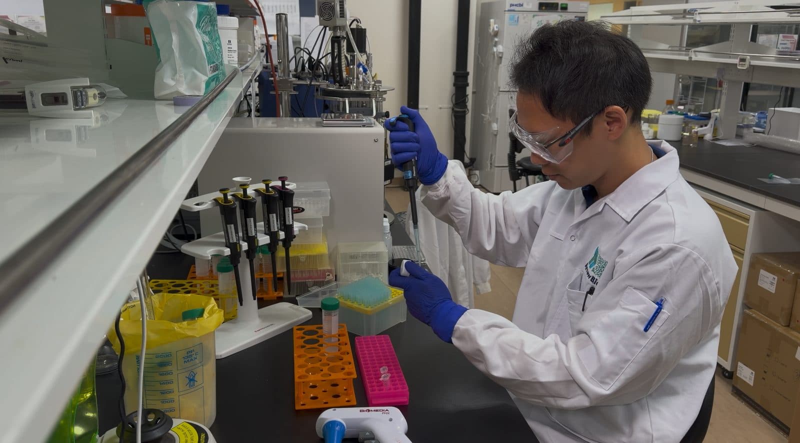 Co-author Fabian Hia pipetting samples at a laboratory bench, wearing safety glasses and gloves